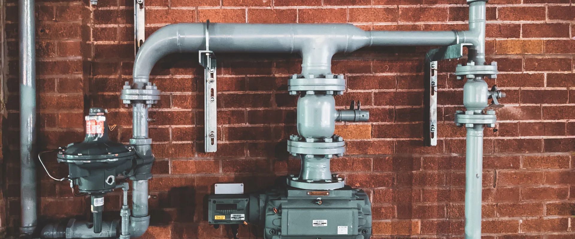 water heater installation grey colored attached to a red bricked wall
